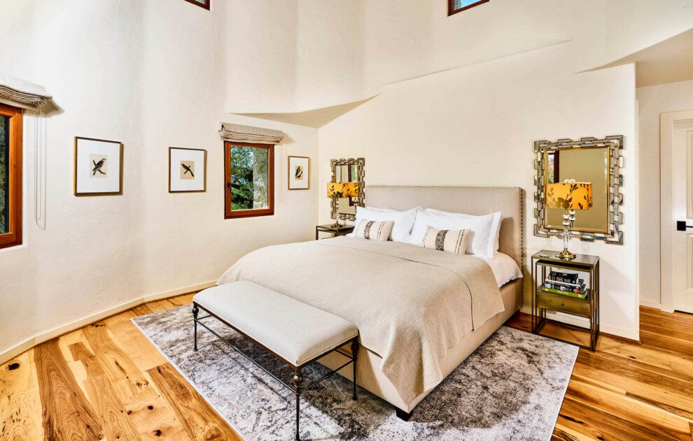 A freshly made bed stands in an airy white room